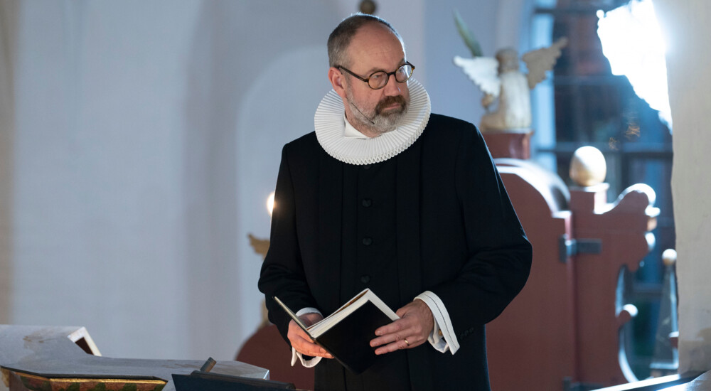 Domprovst Jacob Køhn Andersen i præstekjole med bog i hånden