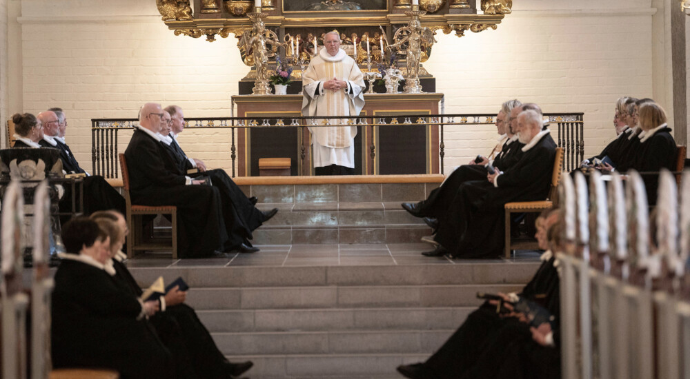 Præster sidder på stole helt oppe foran alteret